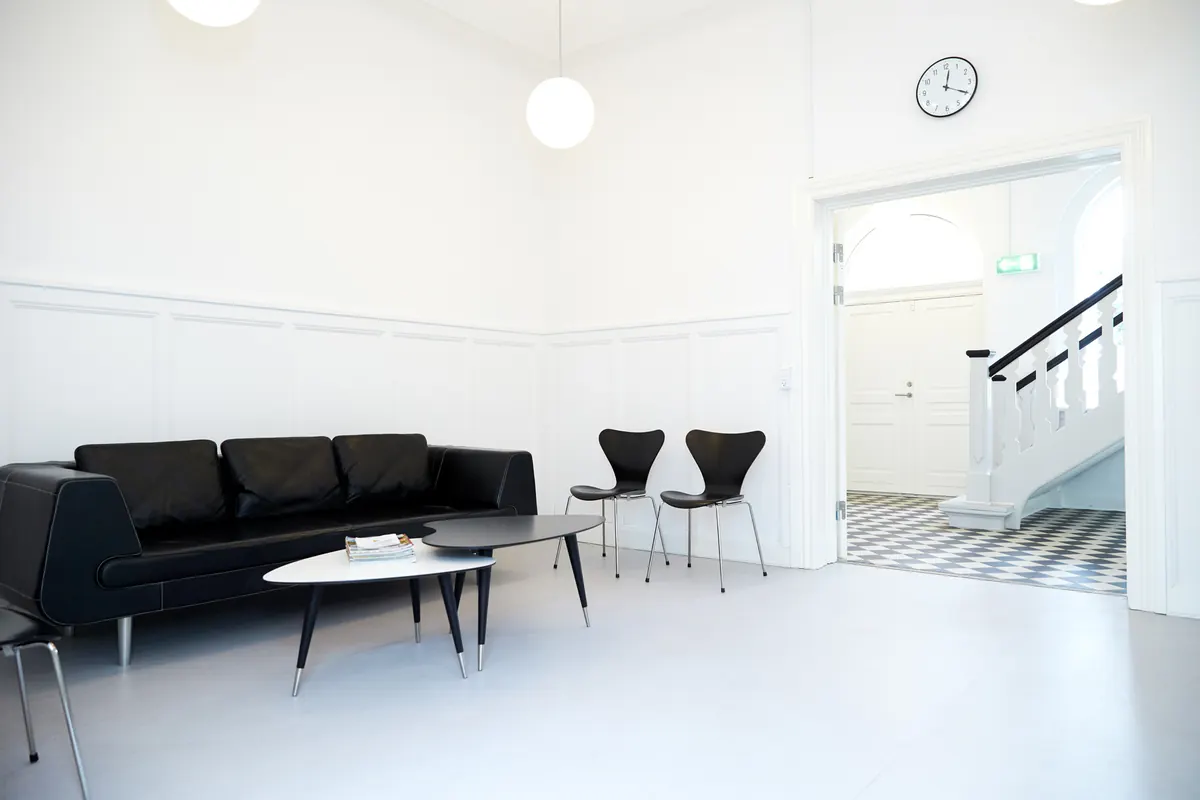 Venteområde med sort sofa og udsigt til den originale trappeopgang.